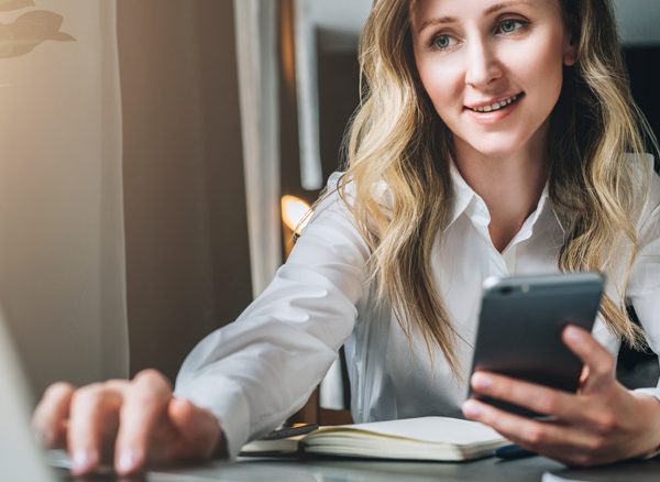 Business woman using laptop while holding cell phone