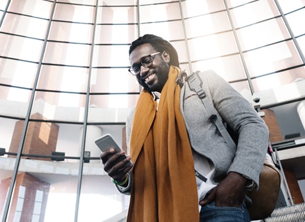 Business traveler standing in airport check-in looking at his phone