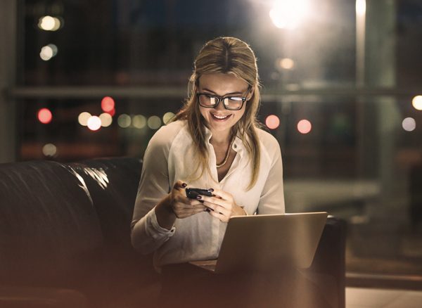 Business traveler in airport lounge in the evening looking at phone