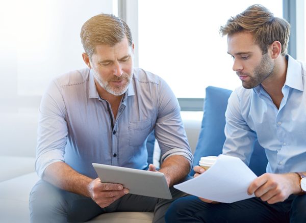 Two business men discussing travel savings while looking at return on investment report