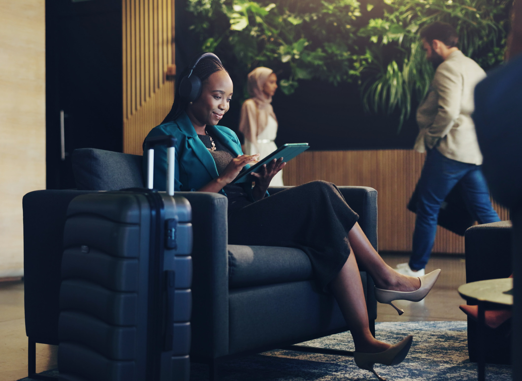 A female business traveler listening to music and scrolling her Ipad in an office loby
