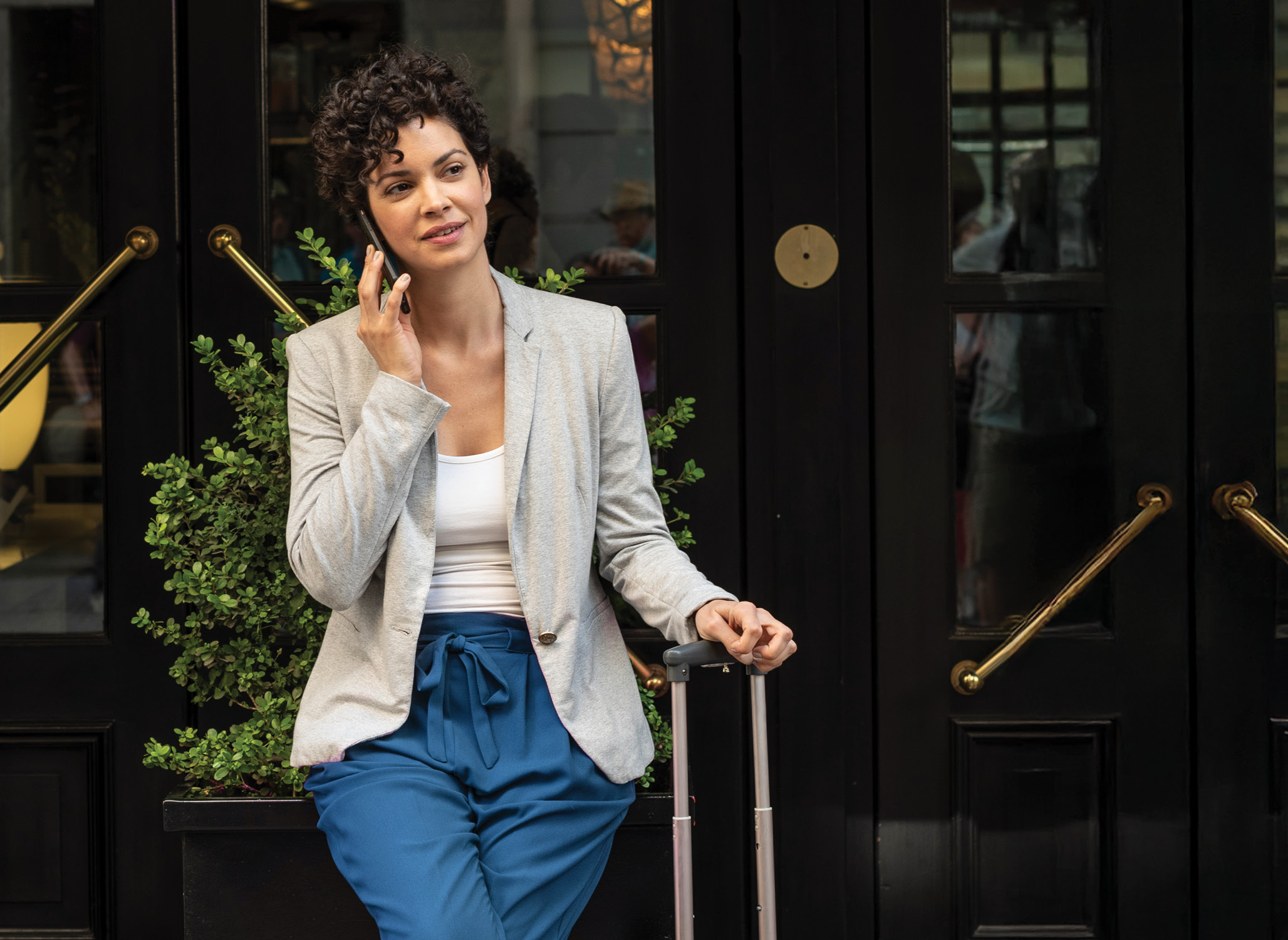 Business traveler sitting outsdie a hotel with her luggage